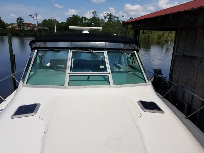 Slide: The Image of 1995 Tiara Yachts 3500 Express docked by a serene lake under a clear sky. - 4