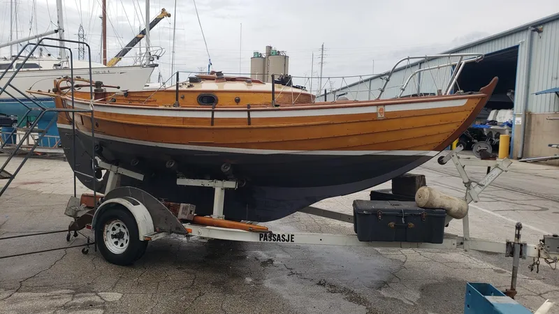 Slide: The Image of Wooden Chip Stulen Faering Design 20 sailboat from 1987 on a trailer in a boatyard. - 4