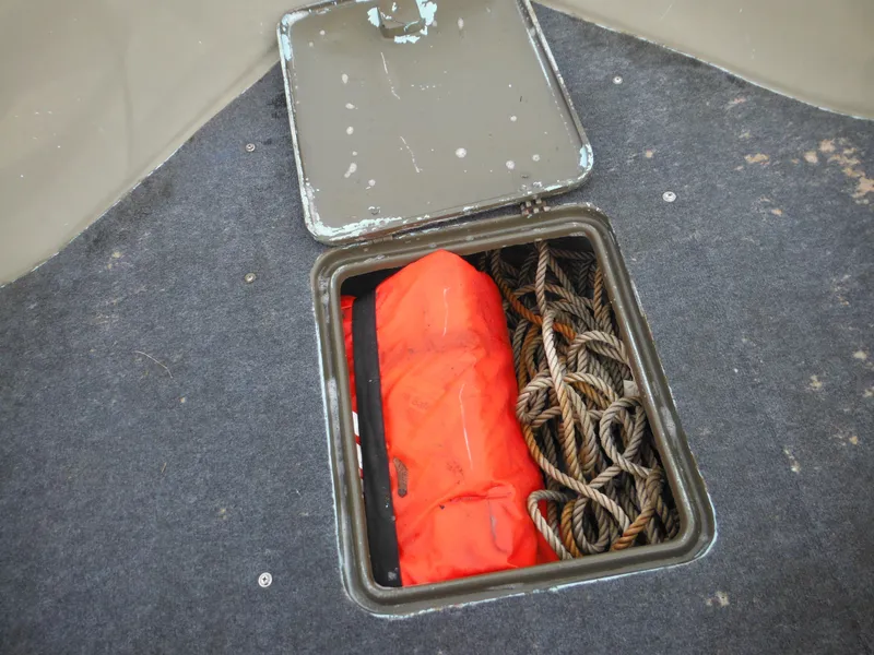 Slide: The Image of Storage compartment of a 1977 McKee Craft 17S boat with rope and life jacket. - 12