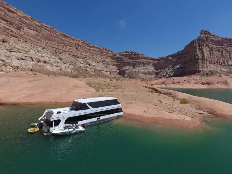 Slide: The Image of Houseboat Bravada Evolution Share #7 docked by rocky shore, 2015 model. - 2