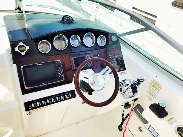 Slide: The Image of 2013 Sea Ray 310 Sundancer helm with gauges, steering wheel, and controls. - 16