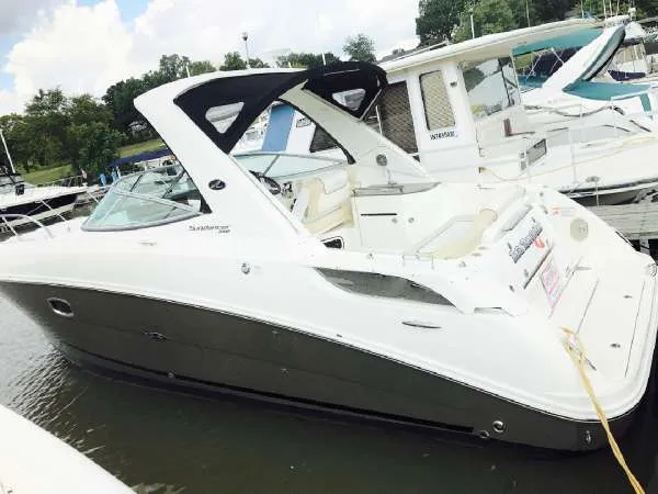 Slide: The Image of 2013 Sea Ray 310 Sundancer boat docked in marina, featuring sleek design and spacious interior. - 2