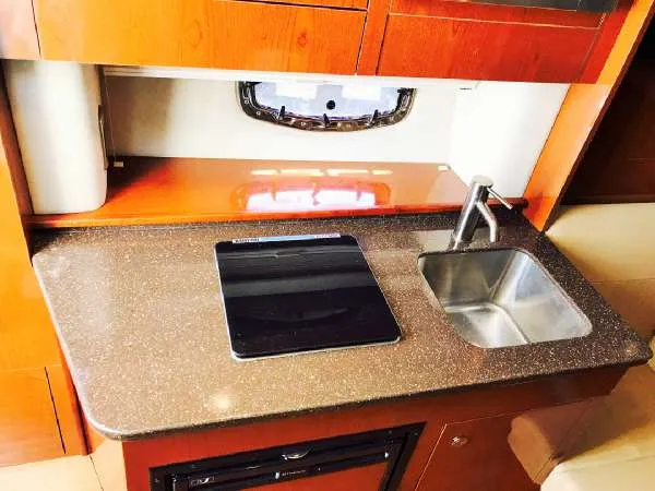 Slide: The Image of 2013 Sea Ray 310 Sundancer galley with sink and stovetop. - 31