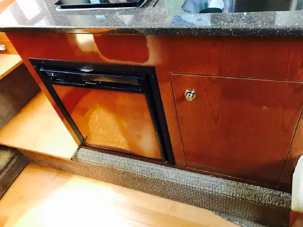 Slide: The Image of 2013 Sea Ray 310 Sundancer interior with wood cabinetry and compact refrigerator. - 32