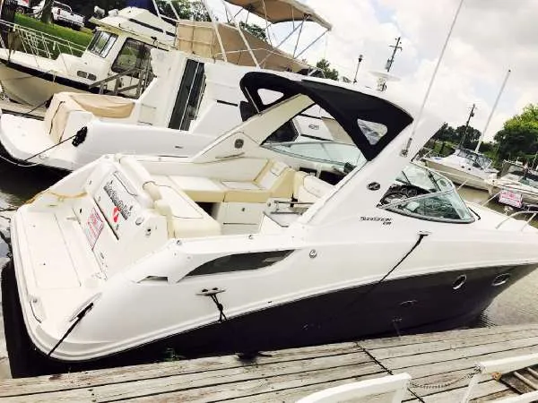 Slide: The Image of 2013 Sea Ray 310 Sundancer docked at marina, featuring sleek design and spacious seating. - 4