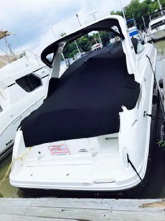 Slide: The Image of 2013 Sea Ray 310 Sundancer docked, covered in black tarp, surrounded by other boats. - 48