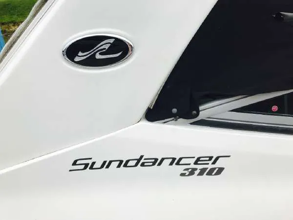 Slide: The Image of 2013 Sea Ray 310 Sundancer boat logo and model name on white surface. - 49