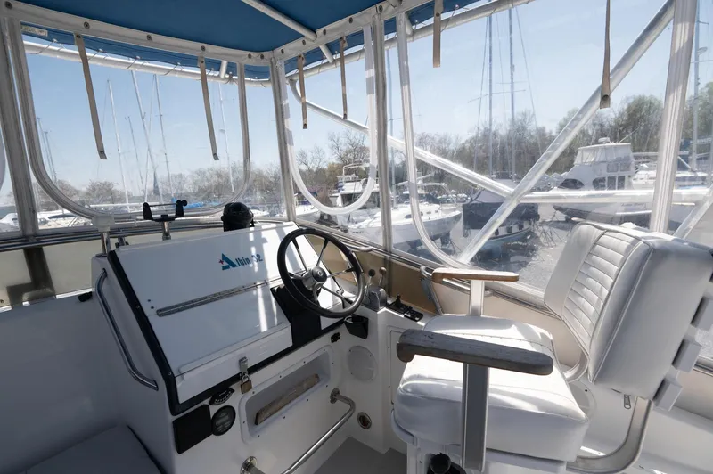 Slide: The Image of 1996 Albin 32 Command Bridge interior with steering wheel and seating, featuring marina view. - 15
