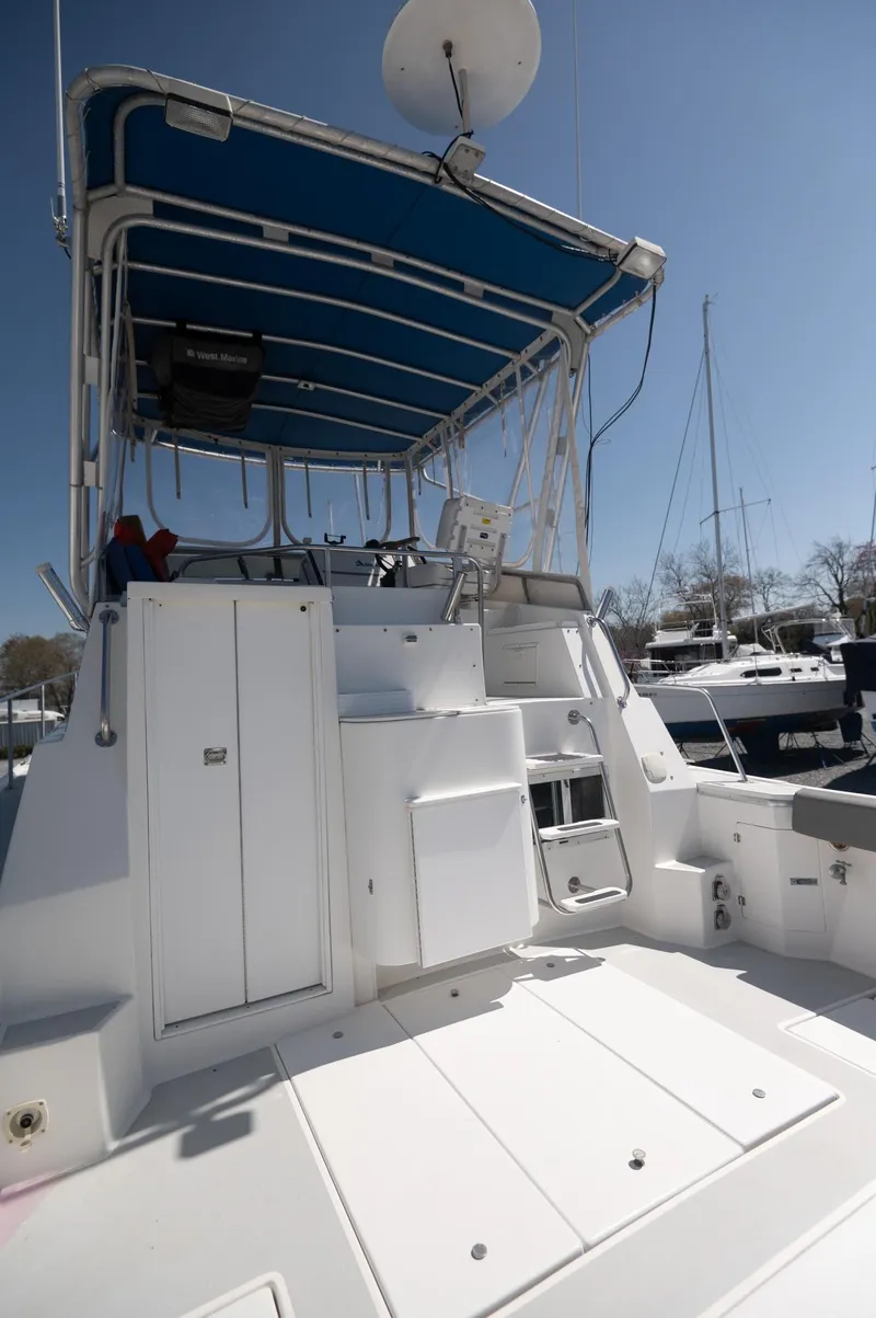 Slide: The Image of 1996 Albin 32 Command Bridge with blue canopy, docked in a marina under clear skies. - 19