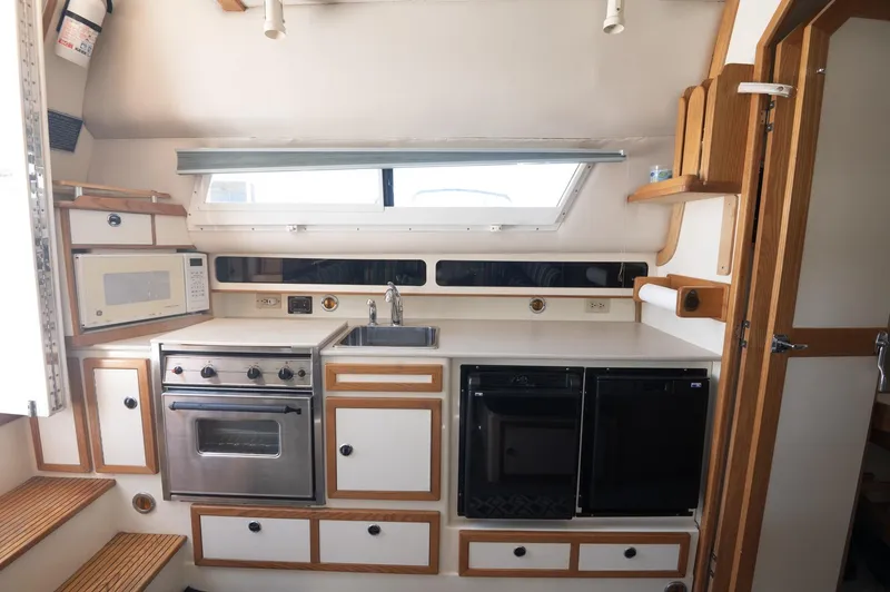 Slide: The Image of 1996 Albin 32 Command Bridge kitchen with stove, microwave, and sink. - 8