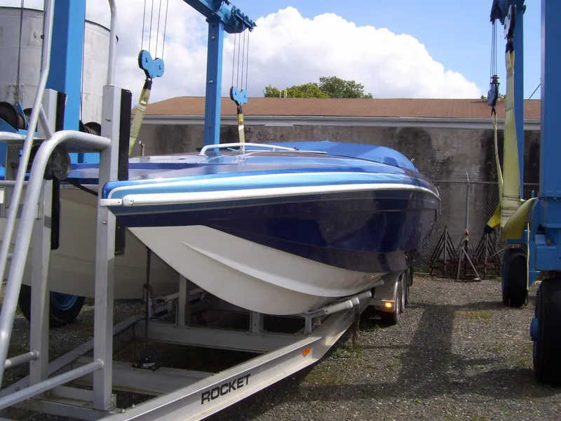 The Image of 2002 Mares 38 High Performance boat on trailer, blue hull, parked outdoors. - 0