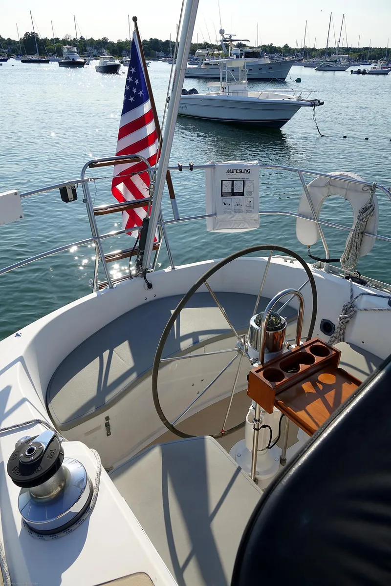 Slide: The Image of Sailboat cockpit with American flag, Nordic 40 model, 1989, in a marina setting. - 94