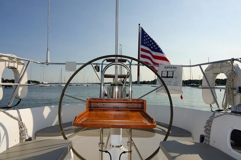 Slide: The Image of Cockpit of 1989 Nordic 40 sailboat with American flag, steering wheel, and wooden table. - 96