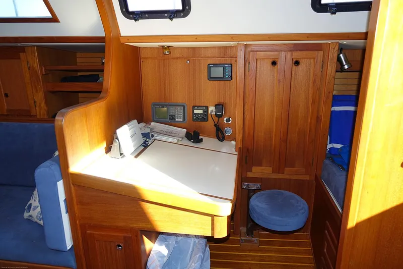 Slide: The Image of 1989 Nordic 40 yacht interior with navigation station, wooden cabinetry, and blue seating. - 99