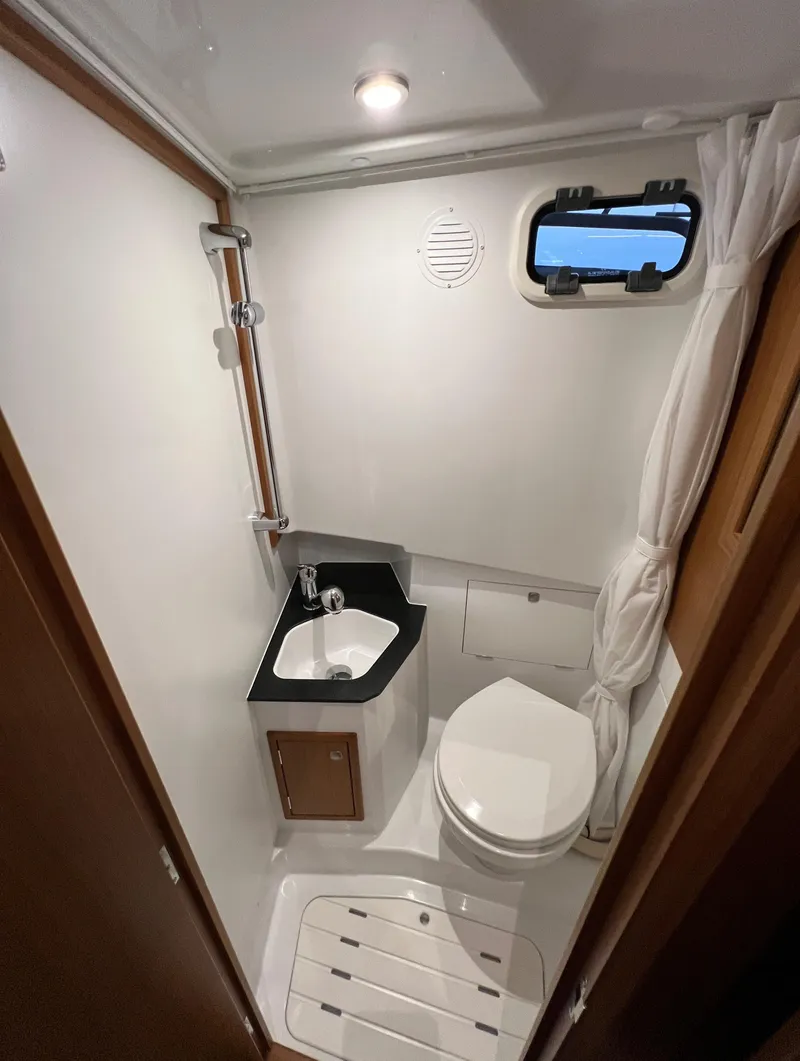 Slide: The Image of 2024 Sargo 28 boat bathroom with sink, toilet, and window. - 19