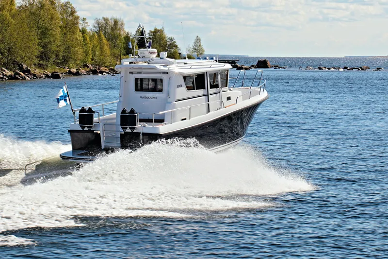 Slide: The Image of 2024 Sargo 28 boat cruising on a scenic lake with trees in the background. - 43