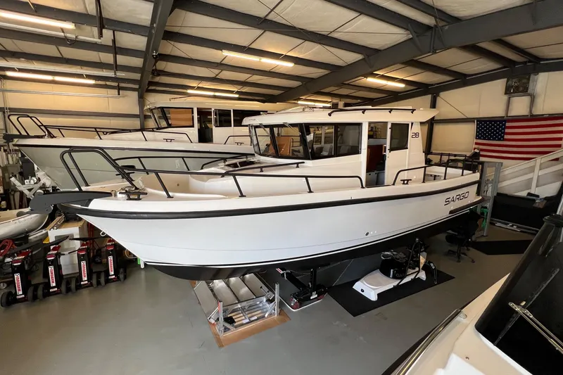 Slide: The Image of 2024 Sargo 28 boat displayed in a showroom with American flag. - 8