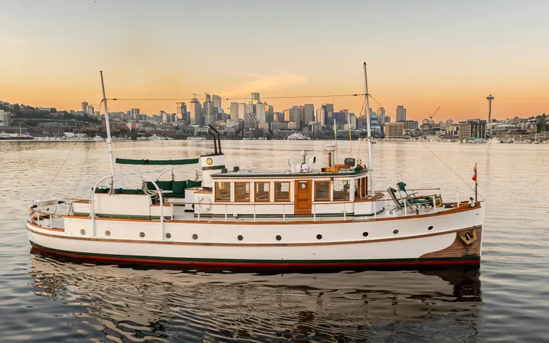 Slide: The Image of Vintage 1931 Boeing Custom yacht on calm water with city skyline at sunset. - 11