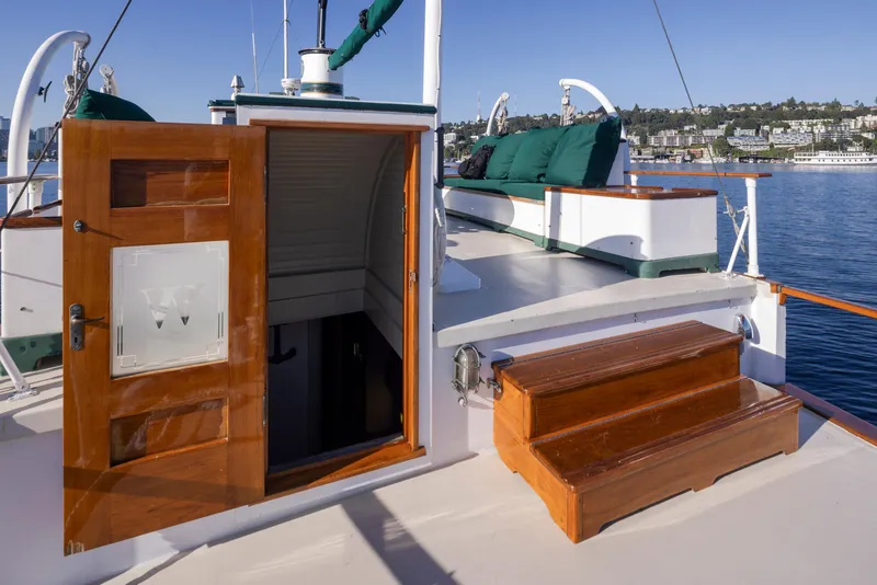 Slide: The Image of Wooden deck of 1931 Boeing Custom yacht with open cabin door and scenic waterfront view. - 23