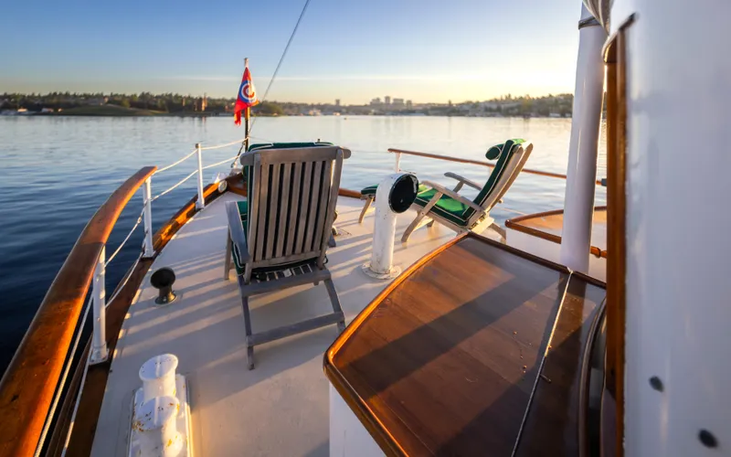 Slide: The Image of Deck of 1931 Boeing Custom yacht with chairs, overlooking calm water at sunset. - 28