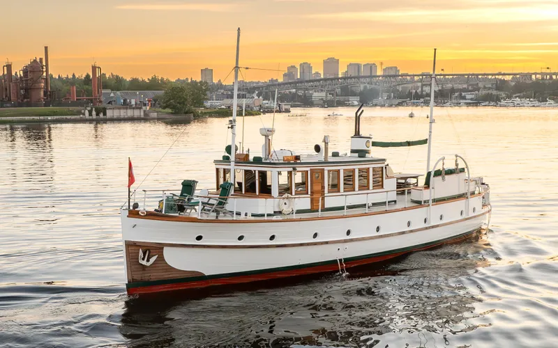 Slide: The Image of Vintage 1931 Boeing Custom yacht on serene water at sunset, cityscape in background. - 4