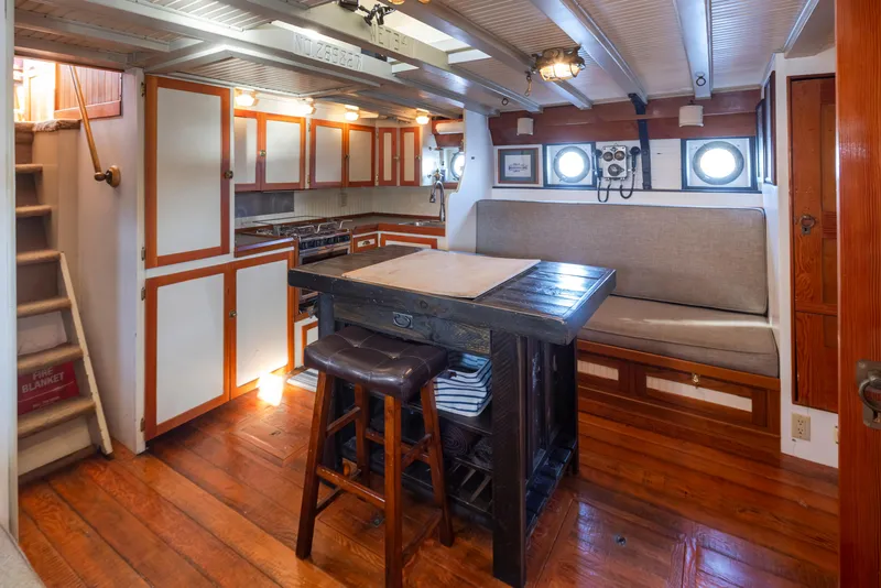 Slide: The Image of Cozy 1931 Boeing custom boat interior with wooden floors, kitchenette, and seating area. - 49