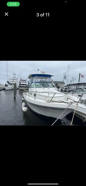 Slide: The Image of 1996 Pro-Line 2950 Mid Cabin boat docked at a marina, featuring a blue canopy. - 3