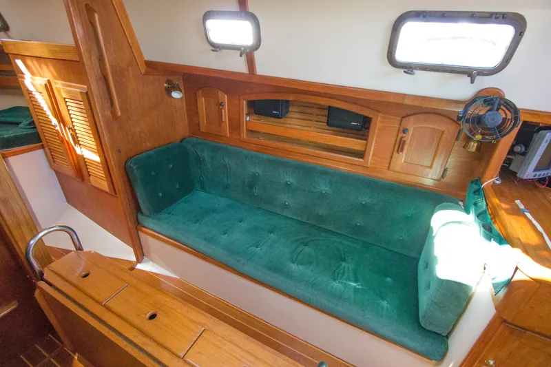 Slide: The Image of Interior of 1992 Pacific Seacraft 34 sailboat with green cushioned seating and wooden cabinetry. - 13