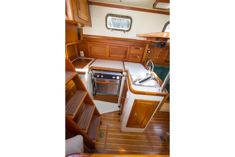 Slide: The Image of 1992 Pacific Seacraft 34 yacht interior with wooden cabinetry and compact kitchen area. - 14