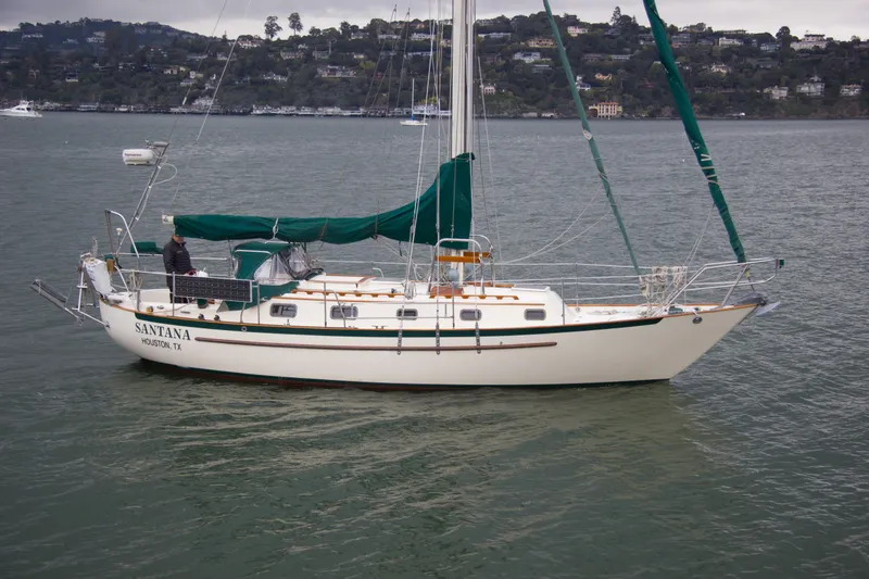 Slide: The Image of 1992 Pacific Seacraft 34 sailboat on calm water, green sails, overcast sky. - 2