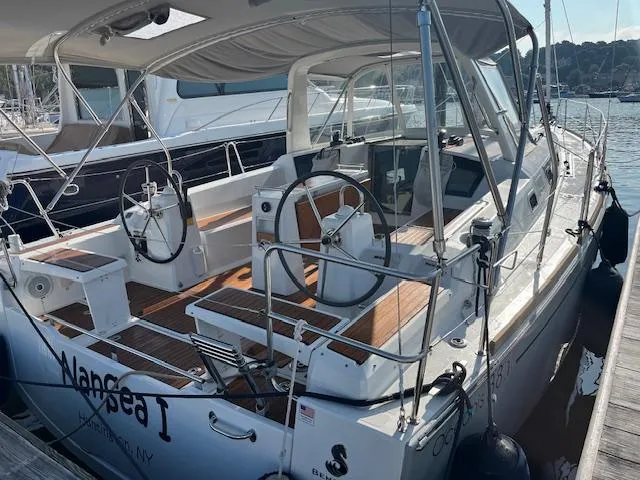 Slide: The Image of 2017 Beneteau Oceanis 38.1 sailboat docked, featuring dual steering wheels and teak decking. - 50