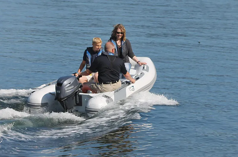 Slide: The Image of 2024 Achilles HB-310AX inflatable boat with three people on a lake. - 3