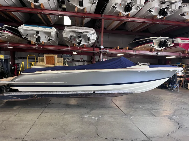 Slide: The Image of 2018 Chris-Craft 27 Launch boat in storage, covered with a blue tarp. - 0