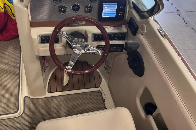 Slide: The Image of 2018 Chris-Craft 27 Launch boat cockpit with wooden steering wheel and modern dashboard controls. - 3