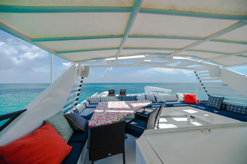 Slide: The Image of Luxurious 1991 Broward Motor Yacht deck with ocean view, shaded seating, and colorful cushions. - 13