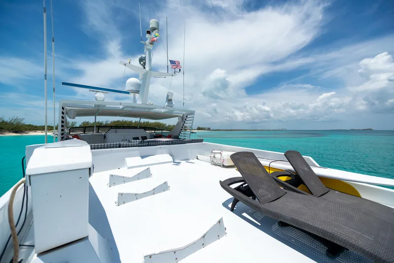 Slide: The Image of 1991 Broward Motor Yacht deck with lounge chairs, clear turquoise water, and blue sky. - 19