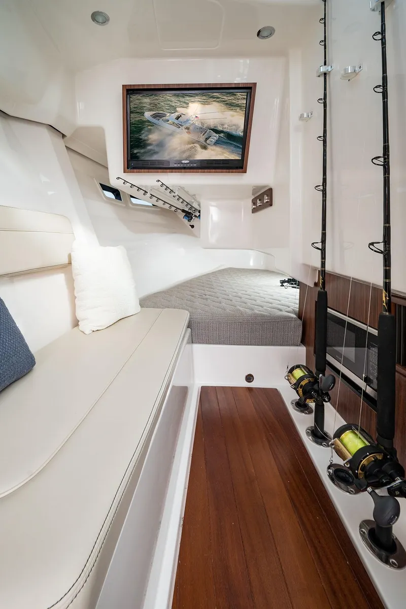 Slide: The Image of Interior cabin of 2025 Pursuit DC 365 Dual Console boat with fishing rods and seating. - 22
