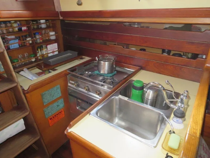 Slide: The Image of 1979 Worldcruiser schooner galley with stove, sink, and spice rack. - 16