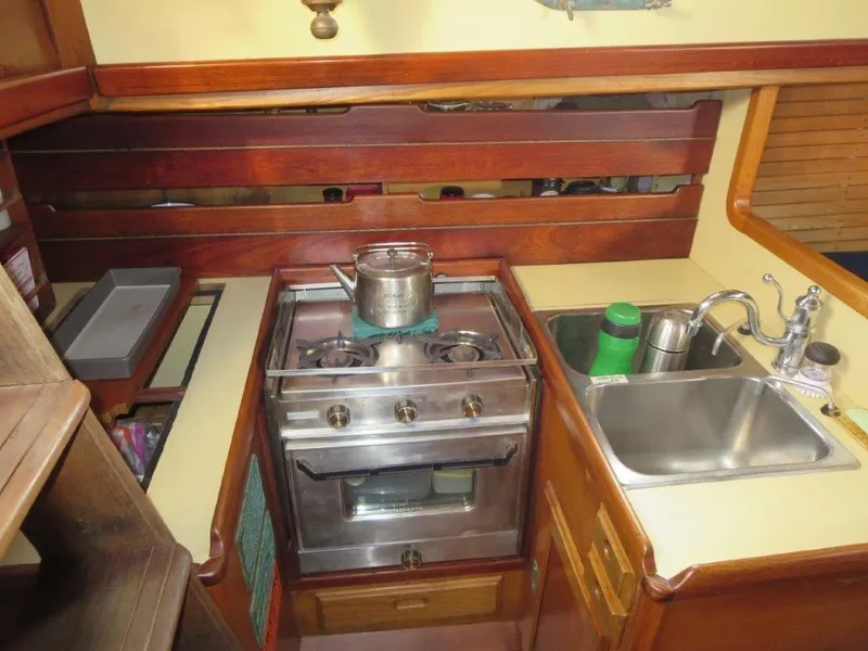 Slide: The Image of 1979 Worldcruiser schooner kitchen with stove, sink, and wooden cabinetry. - 17