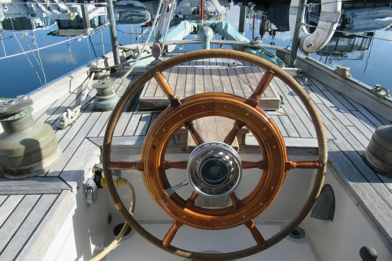 Slide: The Image of Wooden steering wheel on a 1979 Worldcruiser schooner, docked at a marina. - 2