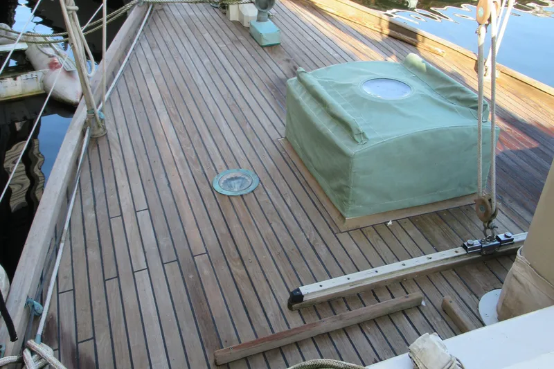 Slide: The Image of Wooden deck of a 1979 Worldcruiser schooner with green cover and nautical equipment. - 22