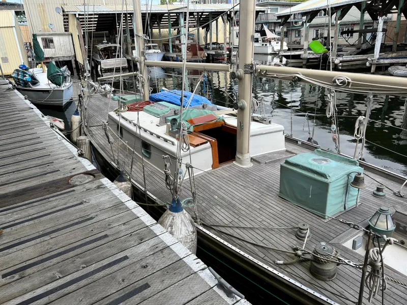 Slide: The Image of 1979 Worldcruiser schooner docked at marina, wooden deck, nautical equipment visible. - 24