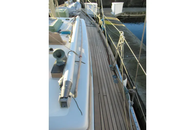 Slide: The Image of 1979 Worldcruiser schooner deck with wooden planks and rigging, docked at a marina. - 5