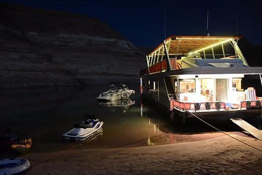 Slide: The Image of Sumerset Red Rocks Trip 5 houseboat docked at night with jet skis and boats nearby. - 6
