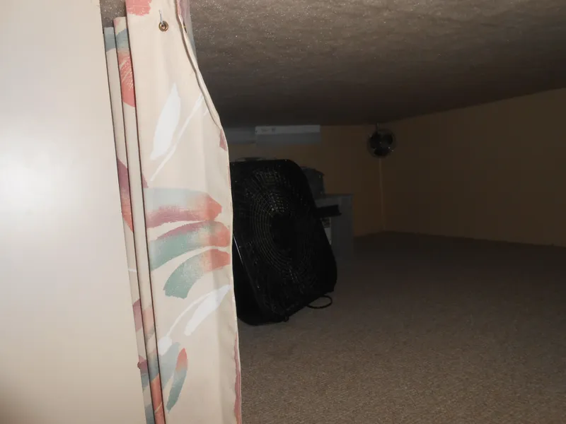 Slide: The Image of 1990 Skipperliner Custom Houseboat interior with floral curtain and fan in a cozy space. - 15