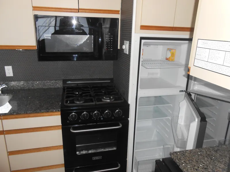 Slide: The Image of Kitchen area of 1990 Skipperliner Custom Houseboat with stove, microwave, and open fridge. - 17