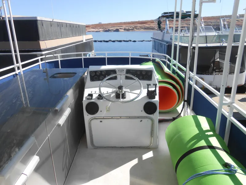 Slide: The Image of 1990 Skipperliner Custom Houseboat helm with green mats and lake view. - 3