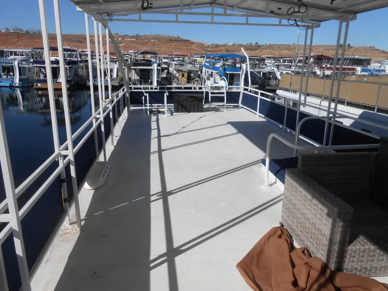 Slide: The Image of 1990 Skipperliner Custom Houseboat deck with seating, docked at a marina. - 5