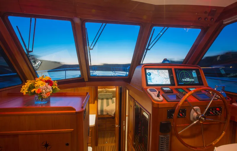 Slide: The Image of 2024 Lyman-Morse HUNT Express Cruiser Flybridge interior with navigation controls and scenic ocean view. - 13