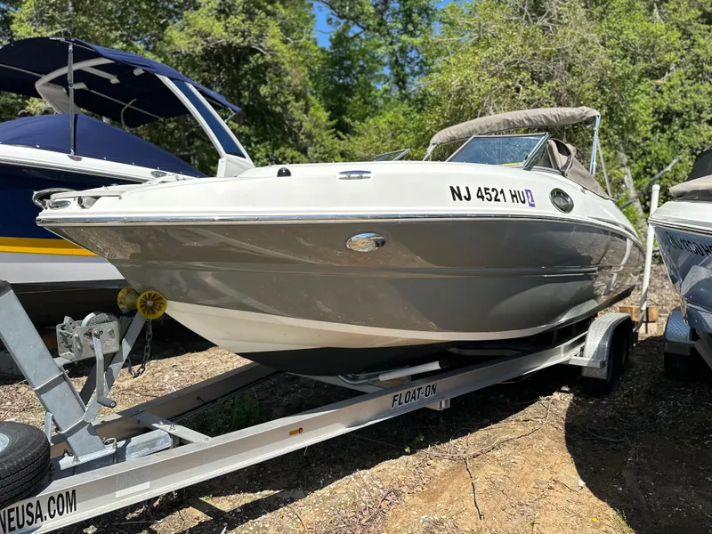 Slide: The Image of 2016 Stingray 234 LR boat on trailer, parked outdoors with trees in the background. - 34